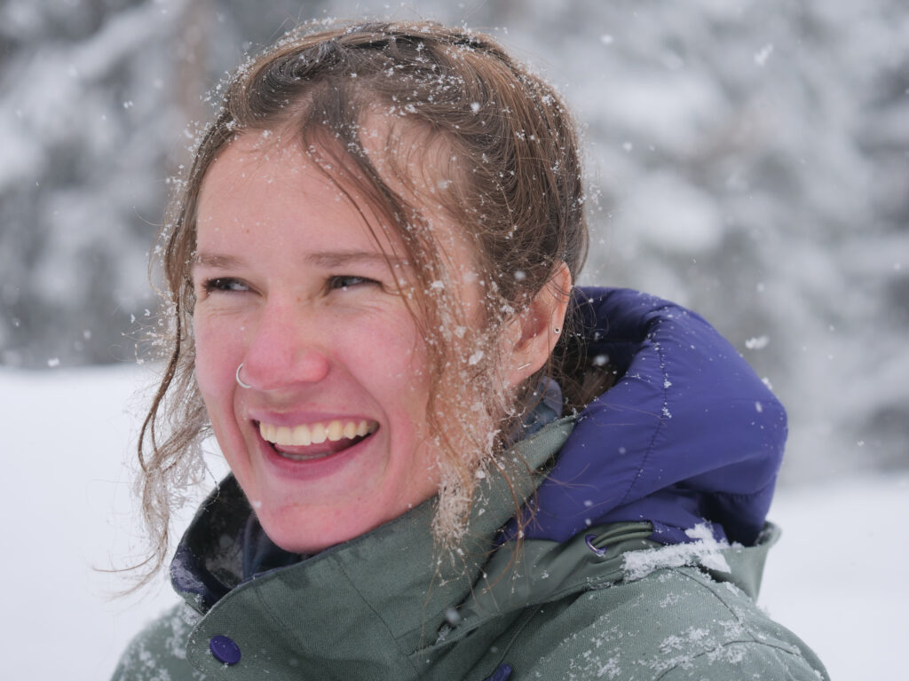 A woman with snow crusted in her hair and a huge smile on her face